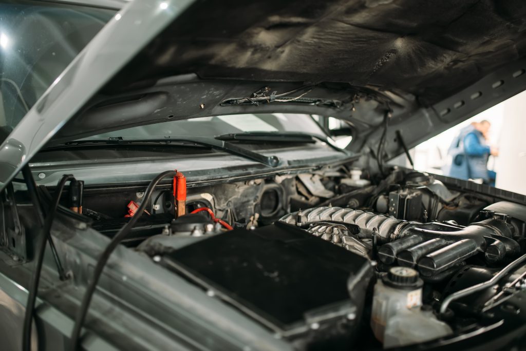 Car with opened hood, wire for battery recharging